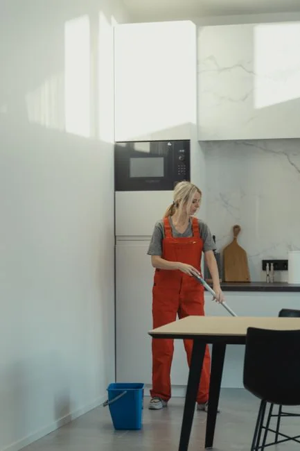 A person in protective gear sanitizing an office desk using fumigation equipment during daytime.